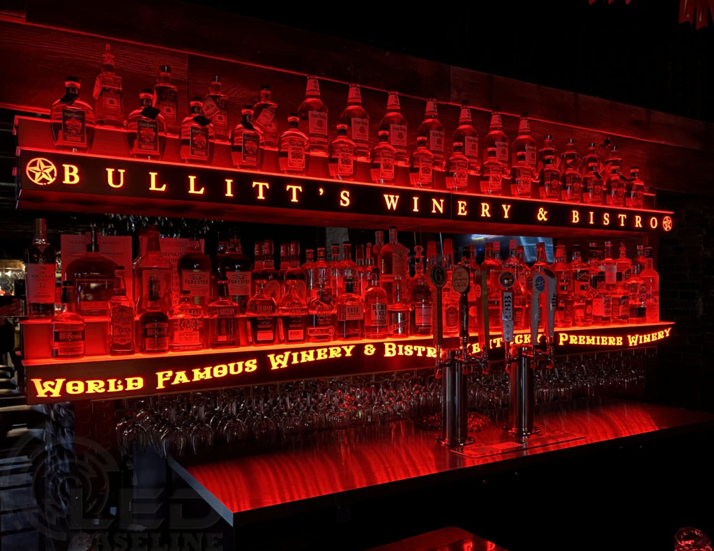 LED backbar lighting illuminating liquor bottles in a commercial bar setting with red ambient glow